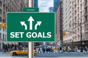 Make sure you set your goals so you know where you're going. Street sign that says "set goals" against a busy city backdrop.