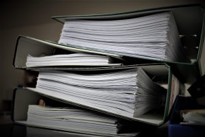 Stack of binders filled with a lot of papers. Leadership needs to focus on results, not compliance.