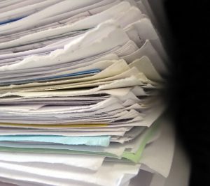 A stack of paperwork. This is what a purchasing staff member's desk can look like. Eliminating it can help reduce transaction costs.