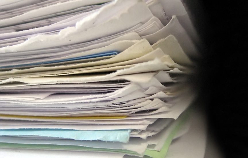 A stack of paperwork. This is what a purchasing staff member's desk can look like. Eliminating it can help reduce transaction costs.