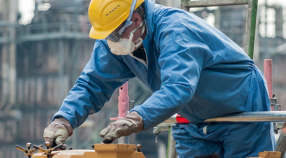 A man wearing coveralls, goggles, a hard hat, bending over a piece of machinery. Most safety issues are caused by either sin of omission or sin of intent. Both are dangerous.
