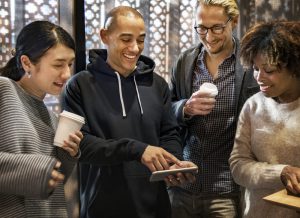 Four people looking at a smartphone at a networking event.