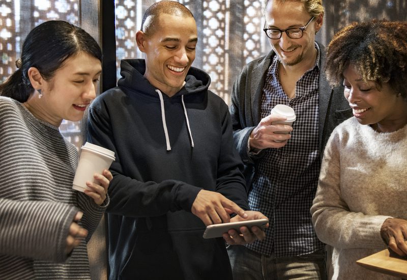 Four people looking at a smartphone at a networking event.