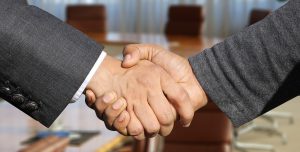 Two men in suits shaking hands. Don't fall in love with your deals.