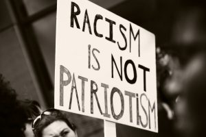 Anti-racism sign held up by a protestor. The sign says "Racism is not patriotism."
