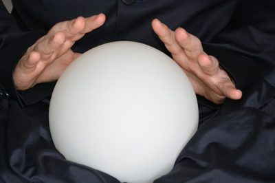 Photo of two hands over a crystal ball. Let's look into it for our manufacturing predictions of 2021.