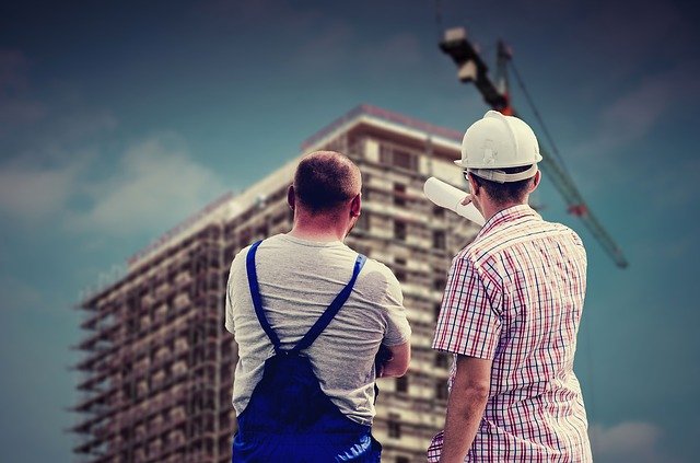 Two workers discussing a building that's being built. It's an illustration for cross-training workers to create positive redundancies in the factory.