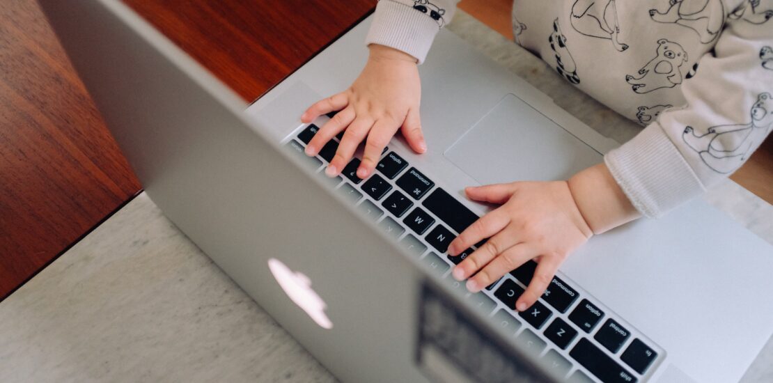 Photo of a baby's hands on a laptop. Represents multigenerational ownership.